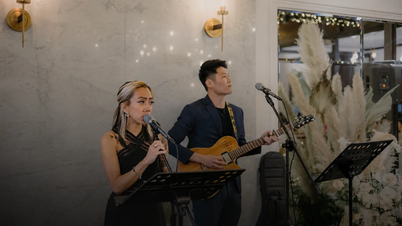 NyaLi singing and Ze playing guitar at a wedding reception